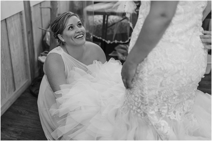 bridesmaid fluffing brides dress before first look